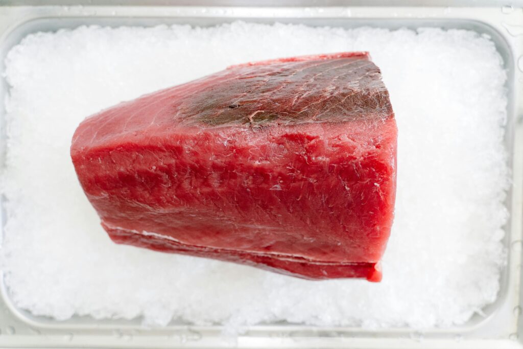 Close-up of a fresh raw tuna steak on crushed ice, ideal for culinary presentations.