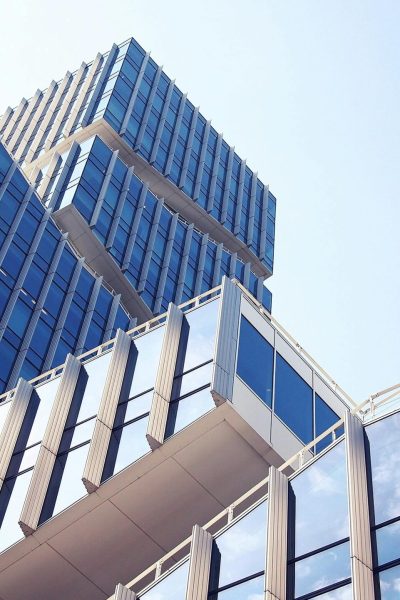 Low-angle shot of a modern skyscraper with reflective glass design under a clear blue sky.